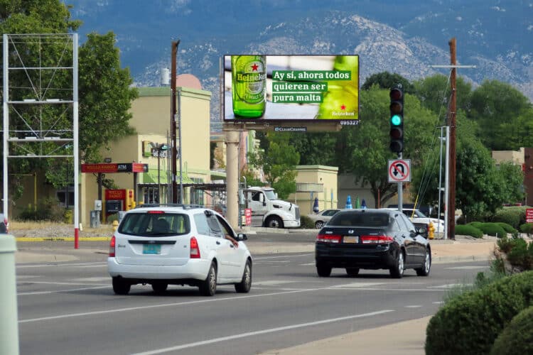 cars on a road driving past a Spanish speaking billboard