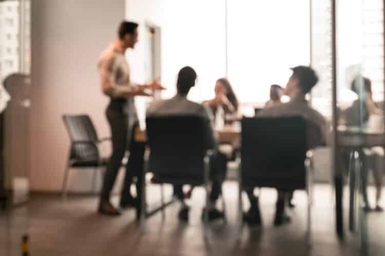 Colleagues having meeting in boardroom, businessman giving speech, blurred photo