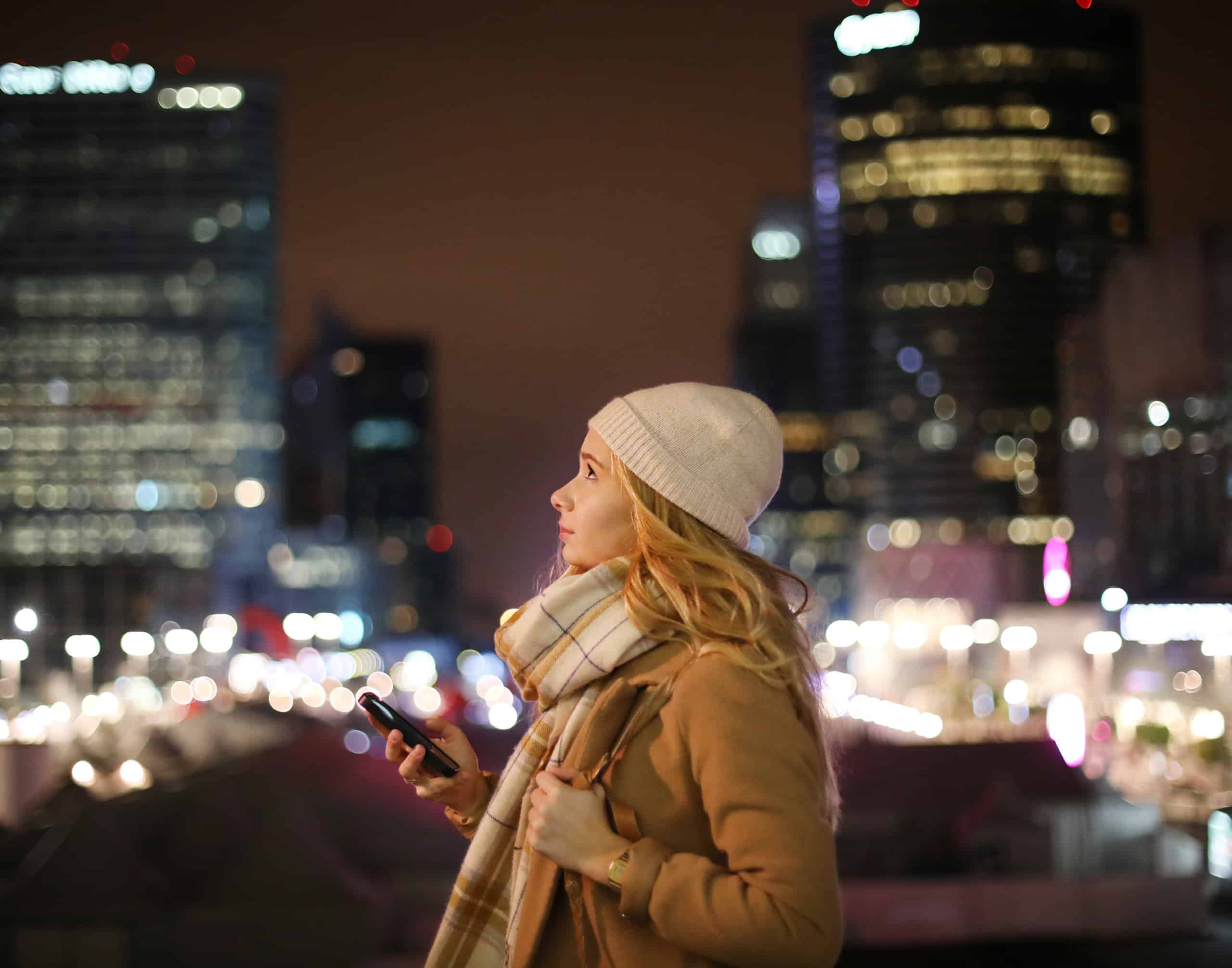 Clear Channel Outdoor - girl downtown at night looking up at billboards